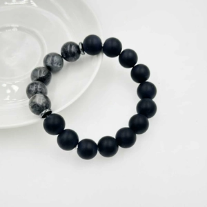 Dettaglio del bracciale con pietre laviche nere opache e perle effetto marmo