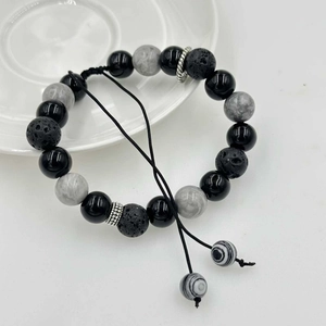 Dettaglio macro di pietre laviche nere e perle marmorizzate su bracciale regolabile