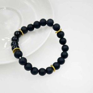 Dettaglio di perle in pietra vulcanica nera opaca e lucida con distanziatori dorati
