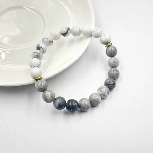 Dettaglio del bracciale con perle di marmo bianco e distanziatori in metallo dorato