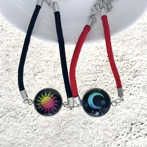 Dettaglio dei ciondoli sole e luna su braccialetti a cordoncino intrecciato per coppie