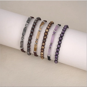 Dettaglio di sei bracciali intrecciati a mano con ametista e pietre occhio di tigre
