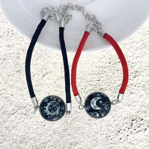 Dettaglio di braccialetti di coppia intrecciati con ciondoli in vetro sole e luna regolabili
