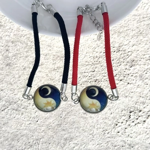 Dettaglio di bracciali intrecciati di coppia con pendenti cabochon in vetro sole e luna