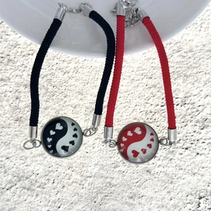 Dettaglio dei bracciali intrecciati coppia sole luna con ciondoli yin yang a forma di cuore