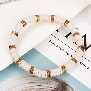 Detail van een bohemien handgemaakte armband met crème heishi kralen en goud