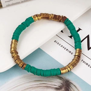 Detail van een bohemien groene en gouden Heishi kralenarmband op een wit plateau