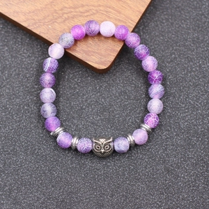 Vue macro des perles d'agate violette à texture patinée et breloque chouette vintage sur bracelet