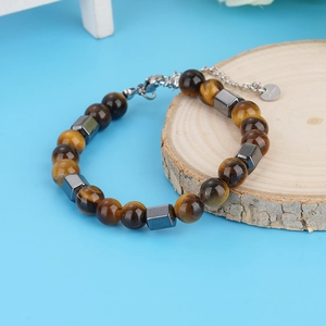 Tiger eye stone bracelet with stainless steel beads on wooden tray and blue background