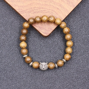 Gros plan détaillé du pendentif hibou sur un bracelet en perles de bois style vintage