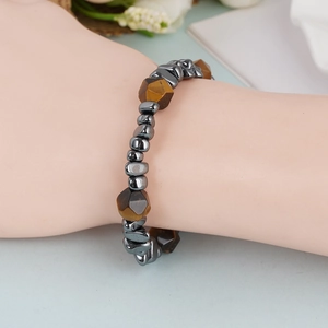 Detail van kralenarmband met bruine tijgeroog en metallic hematiet kralen om de pols