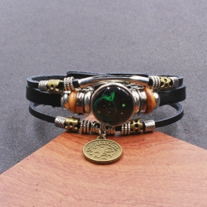 Dettaglio del bracciale in pelle intrecciata Sagittario con perla luminosa e ciondolo in metallo