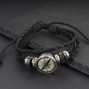 Detailed close-up of multi-layer black leather bracelet featuring a vintage compass ornament