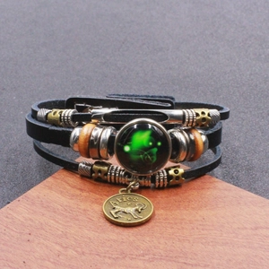Dettaglio del bracciale in pelle intrecciata Ariete con ciondoli vintage e vetro verde