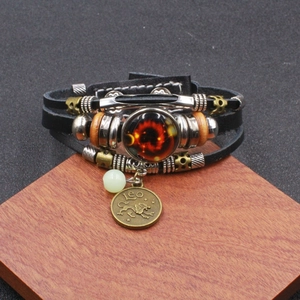 Dettaglio di un bracciale multistrato in pelle con ciondolo Leone e charm in vetro