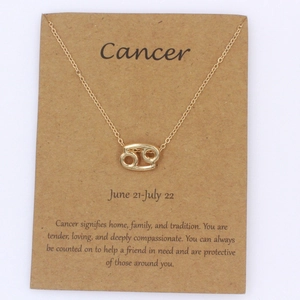 Primer plano del collar dorado signo Cáncer con tarjeta de presentación de cartón kraft