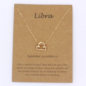 Detalle del collar dorado de Libra sobre una tarjeta con rasgos del signo zodiacal