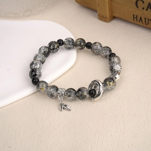 Detailed macro view of natural stone beaded bracelet with silver leaf charm and metal spacer