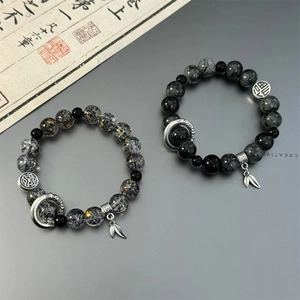 Detailed macro of black rutilated quartz beads and silver lotus charms with zen aesthetic