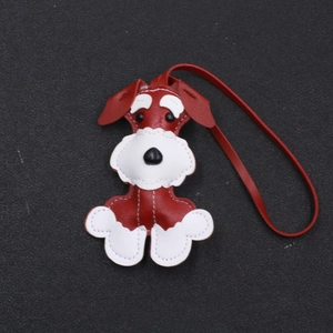 Detail of a handmade Schnauzer leather charm with white stitching and a red leather strap