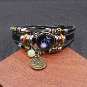 Dettaglio di un bracciale zodiacale Bilancia vintage con cinturini in pelle intrecciata