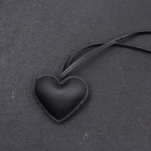 Primo piano di un ciondolo a cuore in pelle nera con cuciture dettagliate e cordino nero