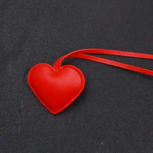 Dettaglio ravvicinato di un ciondolo a cuore in pelle rossa con cuciture coordinate