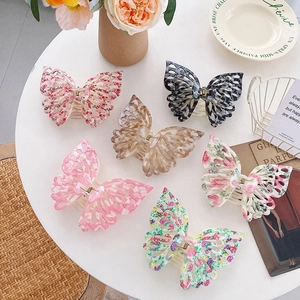 Assorted floral and tortoiseshell butterfly hair claws displayed on a white table