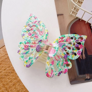 Macro shot of large butterfly hair claw clip with floral print and gold spring detail