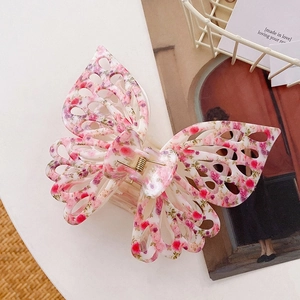 Detail of floral butterfly hair claw clip with hollow wings and gold metal spring