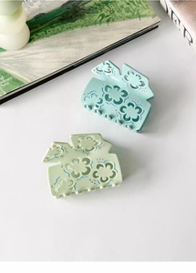 Close-up of acetic acid hair claws with hollow plum blossom design and sparkling rhinestones