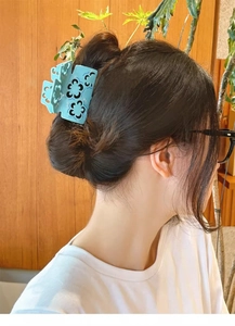 Close-up of light blue acetate hair claw clip with black floral pattern on back of head