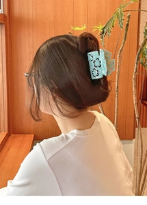 Detail of light blue acetate hair claw clip with floral hollow design worn on hair