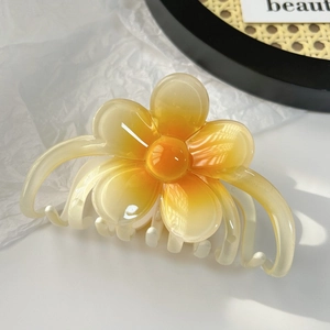 Détail macro de la pince à cheveux dégradée avec pétales de fleurs orange et crème