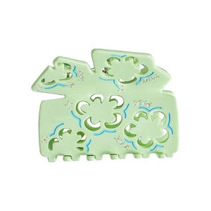 Macro shot of light green acetate claw clip with hollow floral patterns and rhinestones