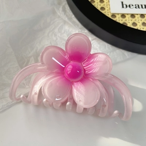 Détail de la grande pince à cheveux en forme de fleur de frangipanier rose dégradé élégante