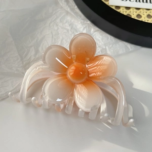 Vue macro de la pince à cheveux dégradé orange en forme de fleur avec finition polie
