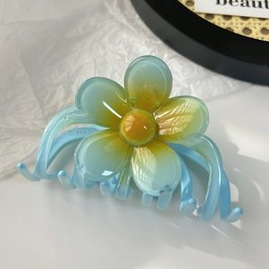 Vue détaillée d'une pince à cheveux fleur dégradée bleue avec centre jaune et dents lisses