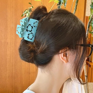 Light blue acetate flower claw clip with hollow floral pattern and subtle glitter finish