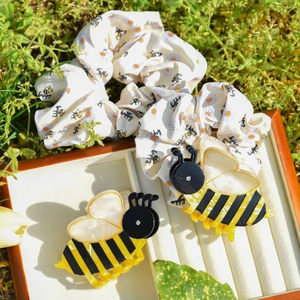 Close-up of acetic acid bee hair clips and floral scrunchie set in a wooden box