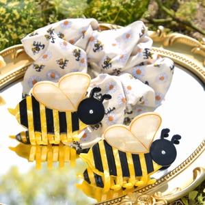 Detailed set of bee claw clips and daisy scrunchie on a decorative mirror