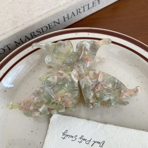 Top view of butterfly acetate hair claw clip with marble texture on ceramic plate
