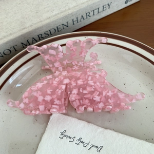 Detailed macro shot of a pink acetate butterfly hair claw clip on a porcelain tray