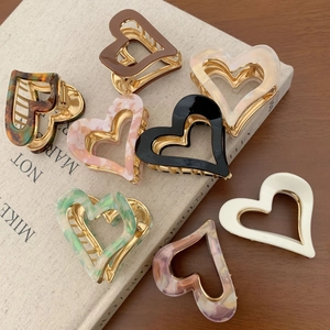 Elegant heart-shaped acetate hair claws in various marble colors with gold metal frames