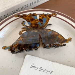 Detailed close-up of tortoise shell butterfly hair claw clip on vintage aesthetic background