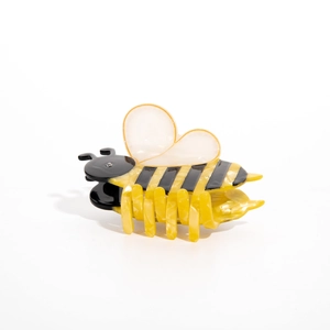 Detailed view of bee-shaped hair claw made of acetate with yellow stripes and rhinestone eye
