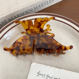 Detailed close-up of tortoise shell butterfly hair claw clip with elegant resin texture
