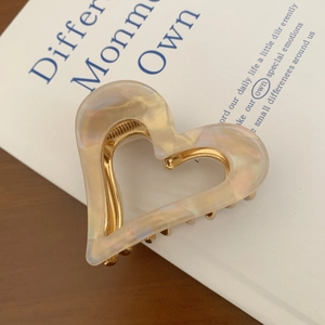 Macro shot of heart-shaped acetate hair claw with champagne marble texture and gold frame