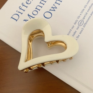 Detailed close-up of cream heart hair claw clip on book for elegant styling