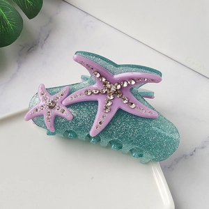 Macro detail of starfish hair claw clip with rhinestones and green glitter finish